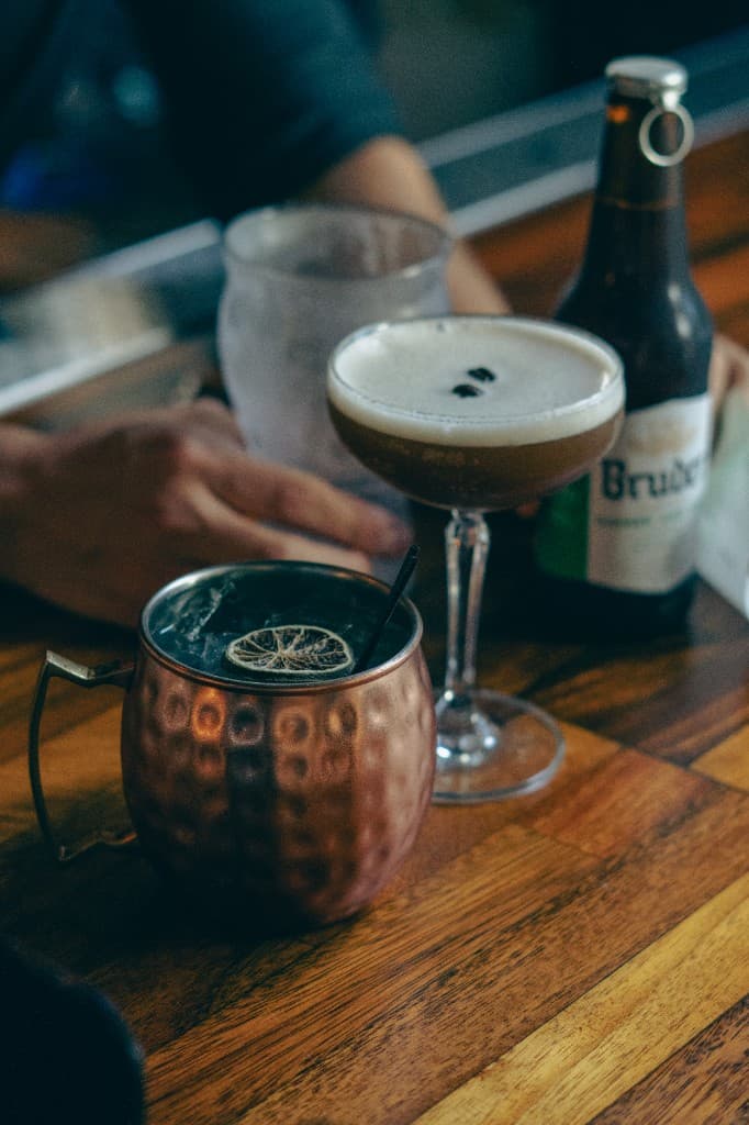 Cocktails and a Bruder beer bottle on a wooden table